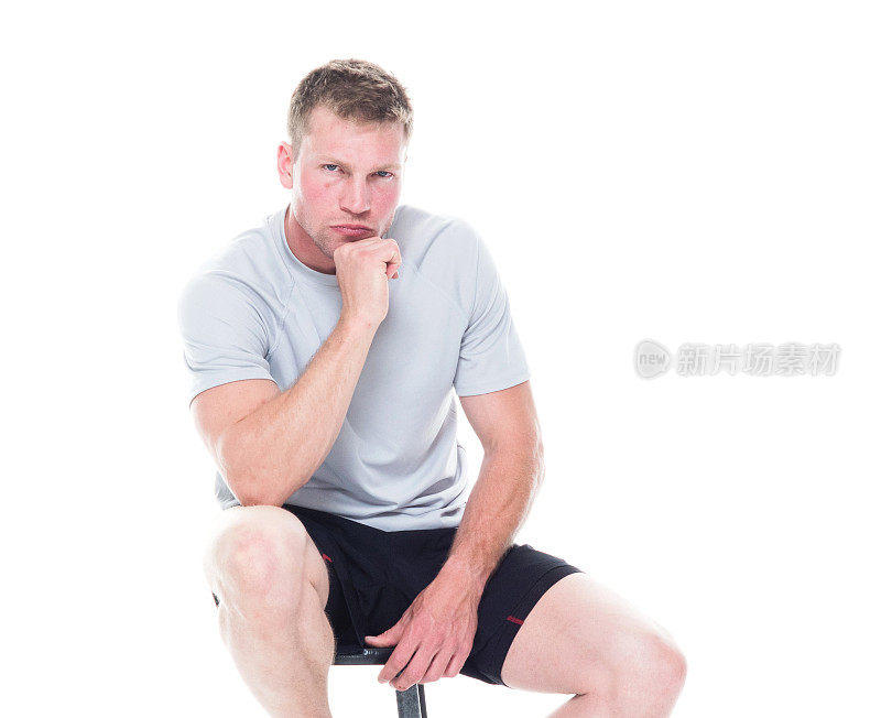 一人/一人/正面视图/腰以上20-29岁英俊的人棕色头发/短发白种人/年轻男子休息在白色背景前穿着跑步短裤/短裤/运动鞋/坐在凳子上